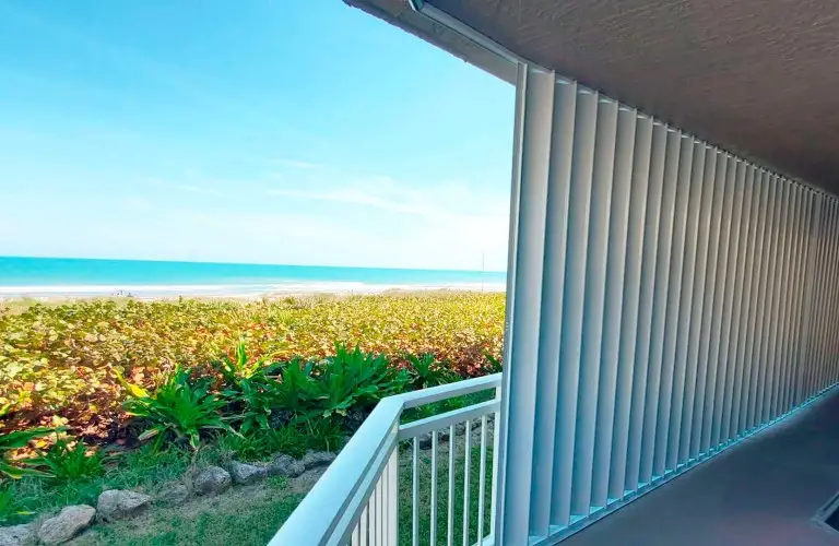 Tropical-style Accordions shutters partially open, providing both shade and storm protection for home windows.